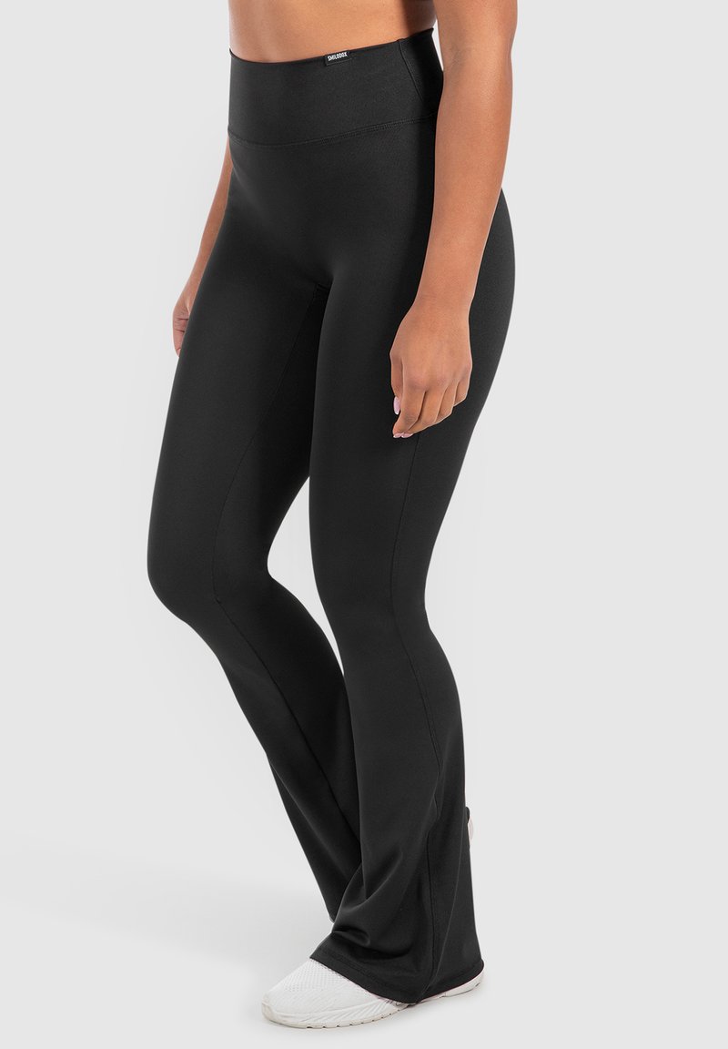 Leggings neri a vita alta realizzati in tessuto elastico, con una texture liscia e un design a campana alla caviglia per un aspetto snello.