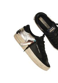 Sneaker nere e argento con parte superiore nera testurizzata, dettagli metallici argento e suola in gomma color crema. Include un'etichetta di branding.