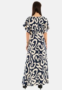 Abito lungo con un motivo astratto blu navy e crema, maniche a sbuffo corte, vita cinchata e tessuto fluido.