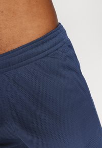Marineblaue, netzartige Sportshorts besitzen eine strukturierte Oberfläche, einen elastischen Bund und Nähte entlang der Seiten für zusätzliche Haltbarkeit.