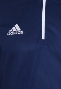 Marineblauw sportshirt van ademend materiaal, met een witte rits en het Adidas-logo geborduurd in het wit op de borst.