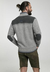 Grauer gestrickter Pullover mit dunkelgrauem Schulterbereich und Ellbogenflicken, ausgestattet mit einem hohen Kragen, gerippten Manschetten und Saum. Mit dezenten blauen Akzenten versehen.