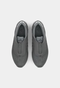 Sive slip-on atletske cipele s teksturiranim gumenim potplatima, zatvaranje na patent zatvarač i akcenti loga na jeziku i stranicama.