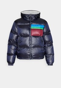 Chaqueta acolchada en azul marino con capucha. Presenta un panel en el pecho de colores rojo, verde y azul. Textura brillante con puños y dobladillo elásticos.