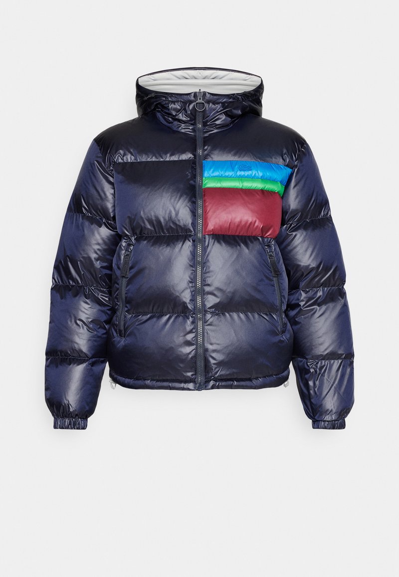 Daunenjacke in Marineblau mit Kapuze. Verfügt über ein buntes Brustpaneel in Rot, Grün und Blau. Glänzende Textur mit elastischen Bündchen und Saum.