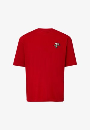 Červené bavlnené tričko s krátkymi rukávmi a okrúhlym výstrihom, so malým vyšívaným dizajnom Snoopy na ľavej strane hrude.