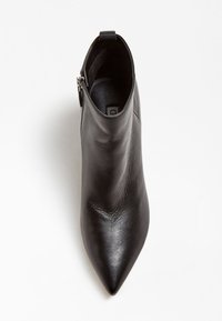 Černá kožená kotníková bota s špičatou špičkou a bočním zipem, pohled shora na bílém pozadí.