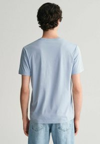 Světle modré tričko s krátkým rukávem vyrobené z měkké bavlny, s kulatým výstřihem a volným střihem. Hladká textura s minimálními detaily.