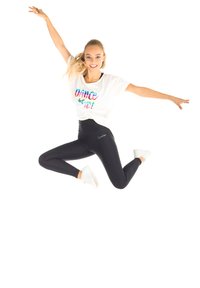 White t-shirt with colorful "DANCE" text, black high-waisted leggings, and white sneakers; model jumping against a white background.