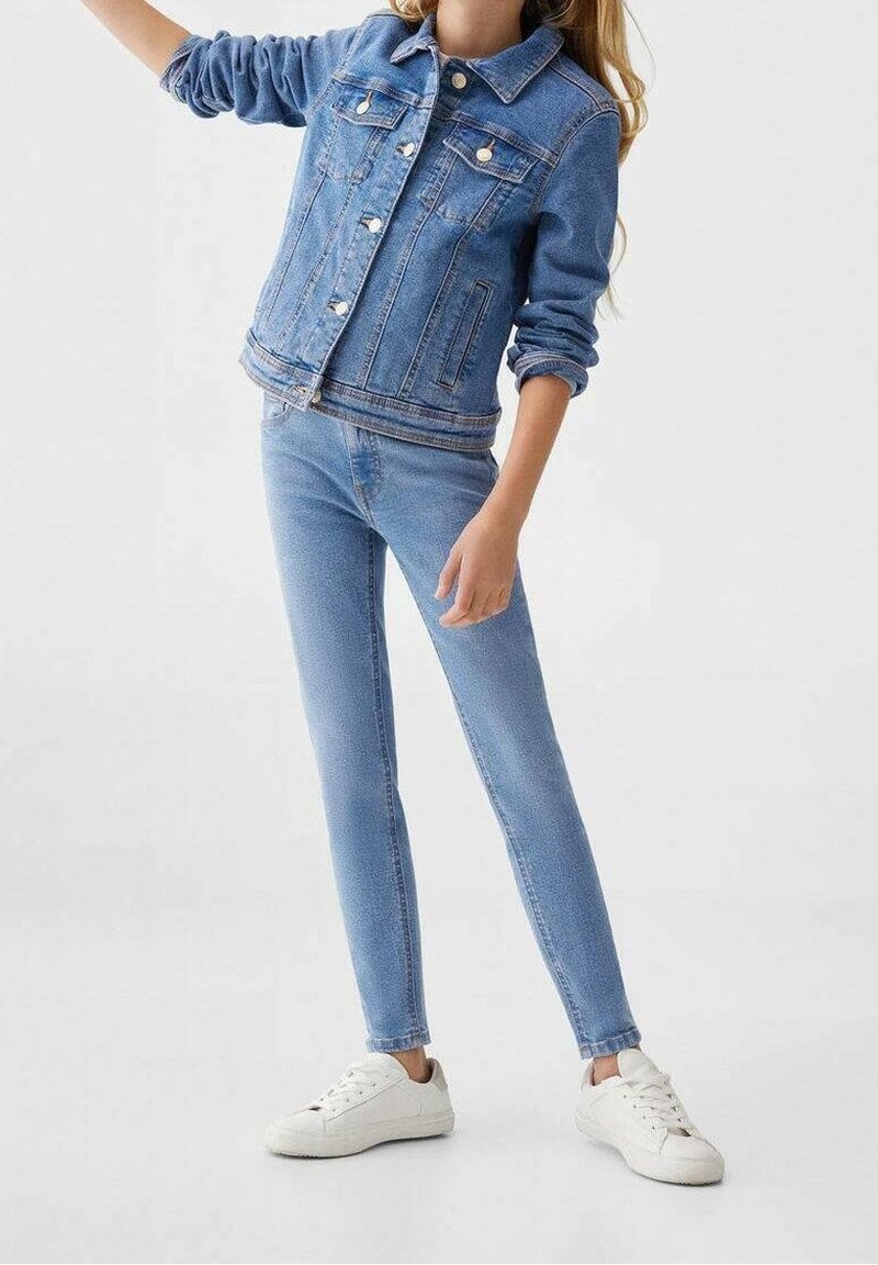 Blå denimjacka med knäppningar, framfickor och uppvikta ärmar; matchad med slim fit blå jeans och vita sneakers.