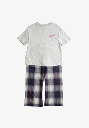 Hellgraues T-Shirt mit kurzen Ärmeln und rotem Aufdruck "Breakfast Crew", kombiniert mit weit geschnittenen, marineblau-weiß karierten Hosen.