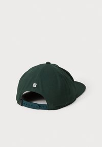 Cappellino verde scuro con visiera curva, con un logo bianco sul retro e una fascia regolabile in plastica. Realizzato in tessuto testurizzato.