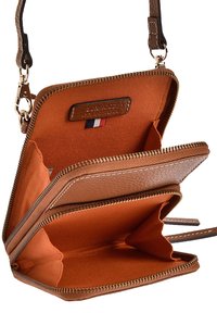 Portefeuille en cuir marron avec fermeture éclair, comportant plusieurs compartiments et une texture lisse. L'intérieur est en tissu orange avec un patch logo.