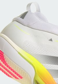 Gros plan sur le talon d’une basket blanche et grise avec des accents de semelle néon jaune et rose, affichant la marque « CrazyFlight 1 » et « Lightstrike Pro ».