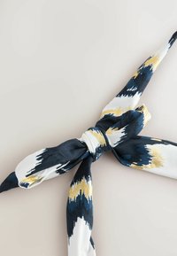 Foulard in seta con un motivo tie-dye in blu navy, bianco e oro, con un design annodato al centro e una texture liscia.