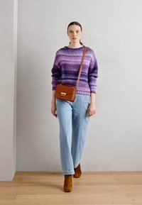 Kötött pulóver lila és rózsaszín árnyalatokban, világoskék bő szárú farmerrel párosítva. Barna kézitáska vállpánttal és bokacsizma.