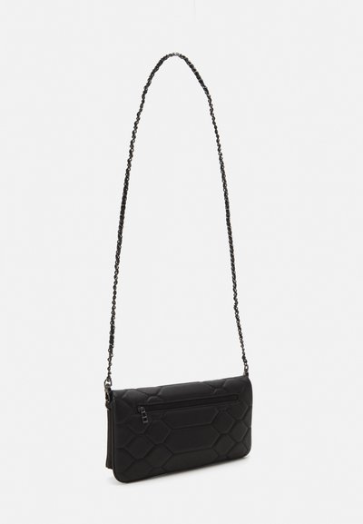 Black quilted crossbody bag with a chain strap, rectangular shape, zippered pocket, and hexagonal pattern on textured surface.