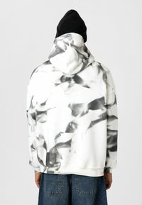 Witte hoodie met zwarte abstracte patronen, vervaardigd uit zachte stof. Heeft een relaxed fit en ribgebreide manchetten.