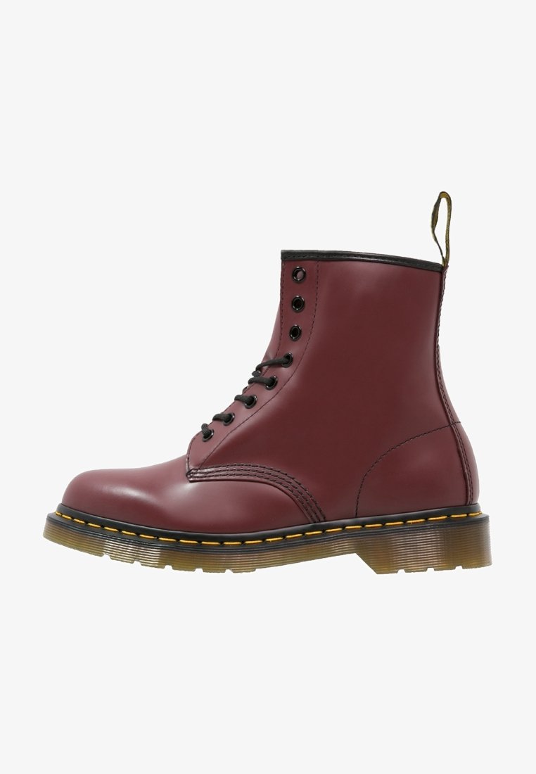 Bottine à lacets en cuir bordeaux avec œillets noirs, coutures jaunes, semelle translucide et languette à l'arrière du talon.