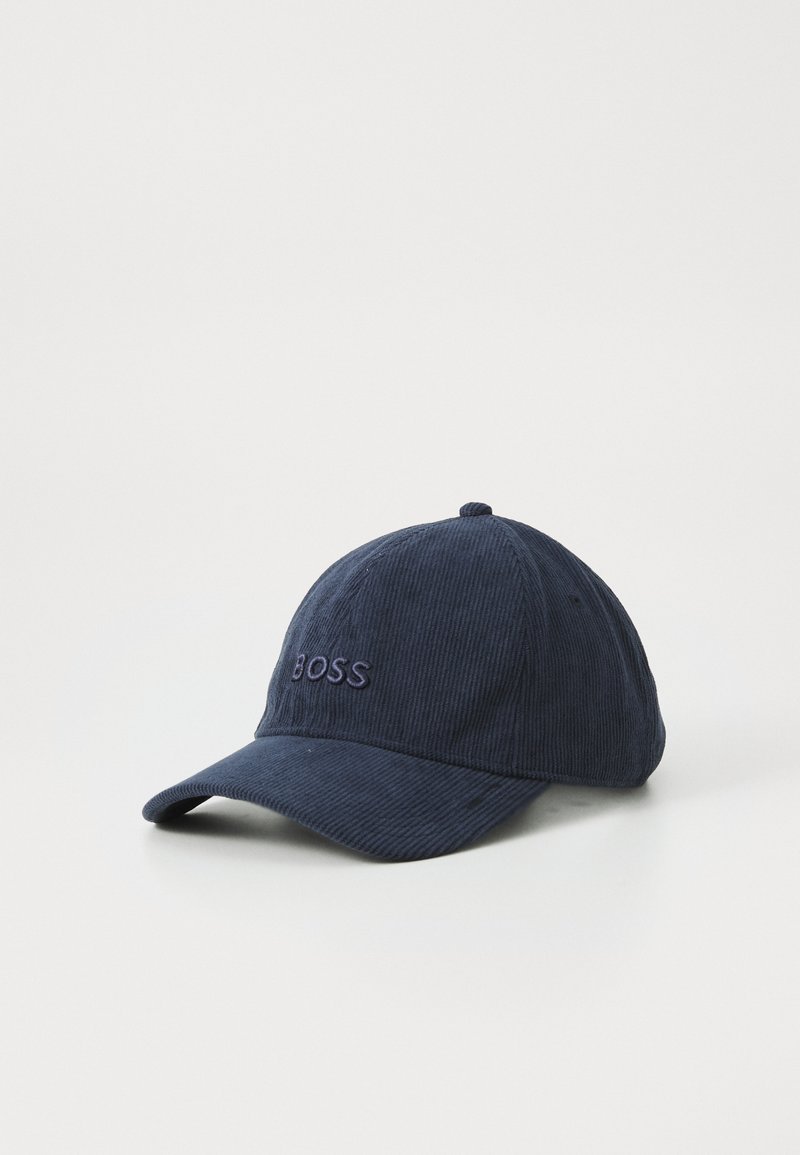Marineblå kordfløjel baseball cap med buet skrb, der har et broderet "BOSS" logo i en mørkere blå farve på frontpanelet. Den teksturerede overflade giver dybde.