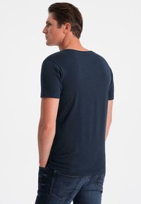 Mørkeblå kortærmet t-shirt lavet af bomuld. Har en rund halsudskæring og en glat tekstur. Bagudsigten viser en afslappet pasform.