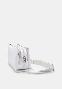 Hvid tekstureret crossbody taske med to lynlåslommer og justerbar rem på en ensfarvet baggrund.