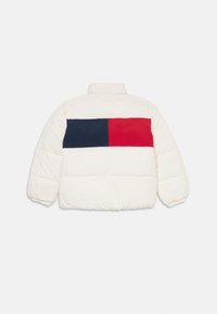 White puffer jacket with a high collar, featuring a large navy and red block design across the back. Elastic cuffs and smooth texture.