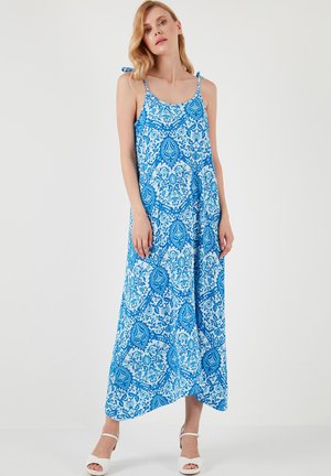 Robe maxi à motifs bleus avec un design fluide, présentant de fines bretelles et un imprimé cachemire dans des nuances de bleu variées.