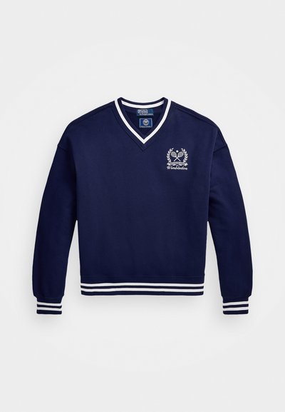 Μπλούζα ναυτικού χρώματος με V-neck, λευκές ρίγες στο τελείωμα και στα μανίκια, καθώς και ένα κεντητό λογότυπο του Wimbledon στο στήθος. Υλικό από μίγμα βαμβακιού.