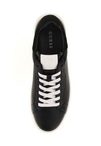 Zapatilla deportiva negra de cuero con cordones blancos, que presenta una parche blanca en el talón y el logo de la marca. Superficie lisa y diseño de punta redondeada.