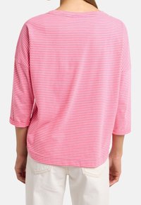 Rosa randig långärmad topp med en avslappnad passform, rundad halsringning och trekvartslånga ärmar. Slät textur med ett lätt tyg.