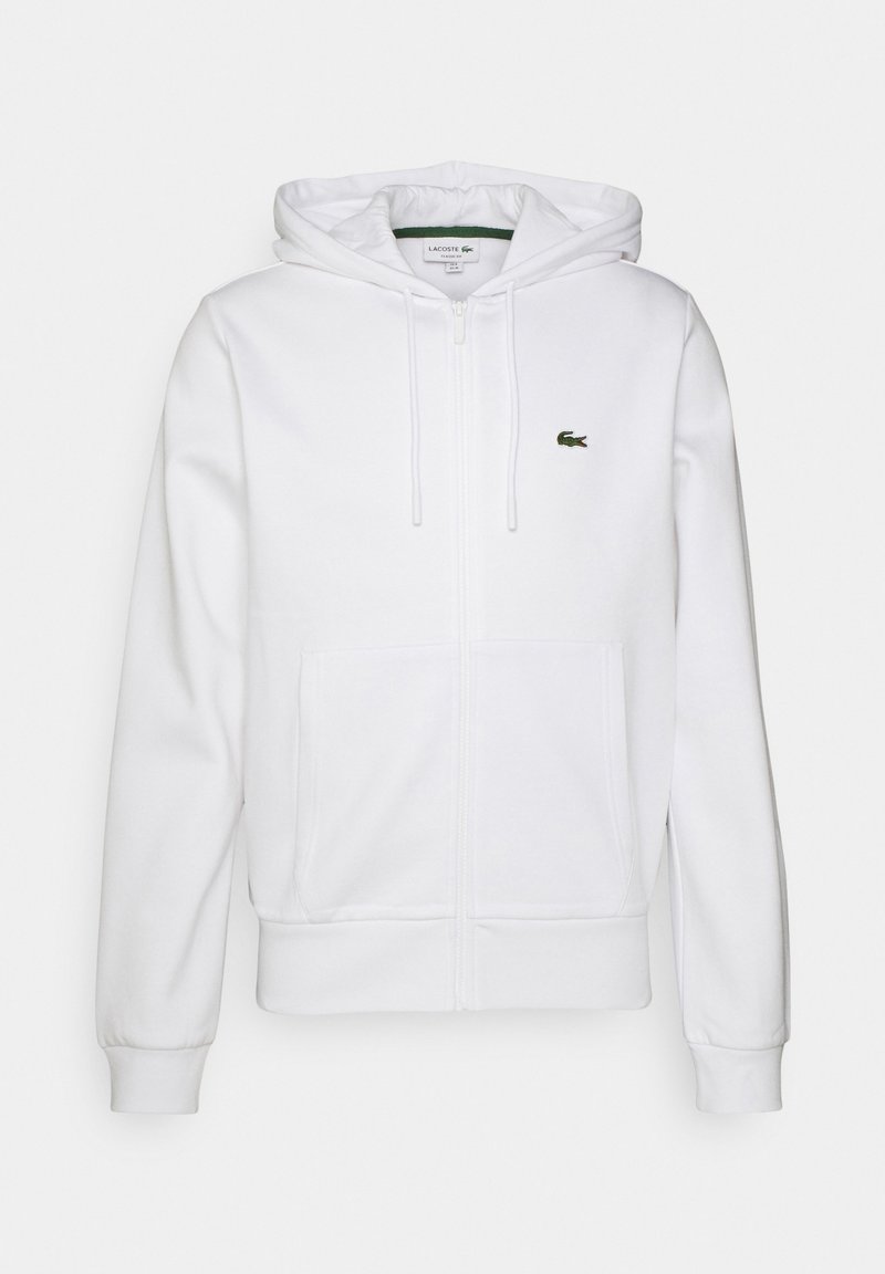 Sweat à capuche blanc zippé avec poches devant, capuche avec cordon, poignets côtelés et petit logo crocodile vert sur la poitrine.