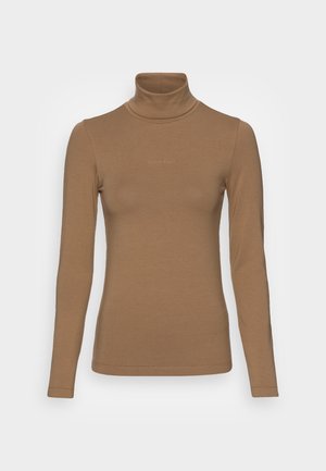 Brun langærmet rullekraveskjorte med diskret Calvin Klein-logo på brystet, vist mod en ensartet lys grå baggrund.
