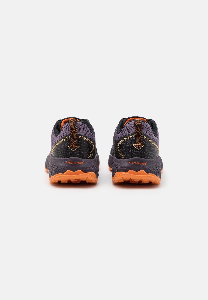 Schwarze und lila Sportschuhe mit strukturiertem Finish, ausgestattet mit orangefarbenen Akzenten und einer gepolsterten Sohle für zusätzlichen Komfort und Unterstützung.