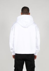 Hvid hoodie med justerbar snor i hætten, lange ærmer, ribbet manchetter og en afslappet pasform, parret med sorte cargo bukser.