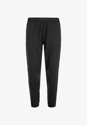 Schwarze Sporthose mit elastischem Bund, die eine glatte Textur, ein tailliertes Design und dezente Markeninschriften im Stoff aufweist.