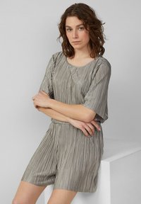 Lichtgrijs geplooid outfit met korte mouwen en shorts. Zachte textuur, ronde hals, en elastische tailleband, met verticale streepjes.