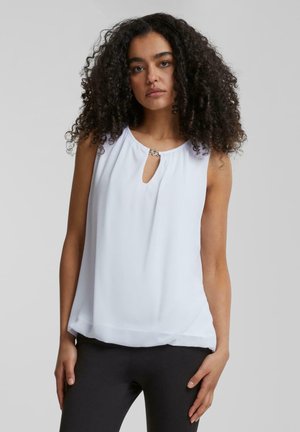 White sleeveless top with a round neckline and small keyhole detail, featuring a decorative metal accent. Smooth fabric with a loose fit.