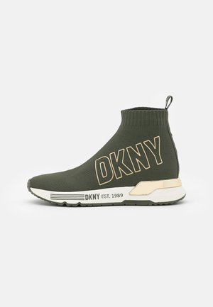 Basket style chaussette vert foncé avec logo DKNY beige et semelle, languette au talon, col de cheville côtelé et « DKNY EST. 1989 » sur la semelle intermédiaire.