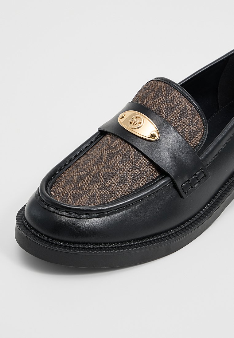 Zwarte leren instapper met een bruin, gestreept stoffen bovenwerk, gouden ovale embleem met initialen en gedetailleerde zwarte stiksels op de zool en het bovenstuk.