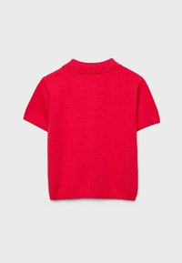 Polo en maille rouge à manches courtes avec un col plié, présenté de dos sur un fond gris.