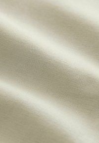 Tela de color beige claro con una textura suave y un sutil patrón de tejido diagonal, que presenta caídas suaves y un ligero brillo.