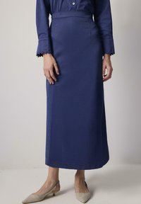 Gonna maxi blu navy realizzata in tessuto liscio con vita aderente e sottili spacchi laterali. Abbinata a scarpe slingback beige chiaro.