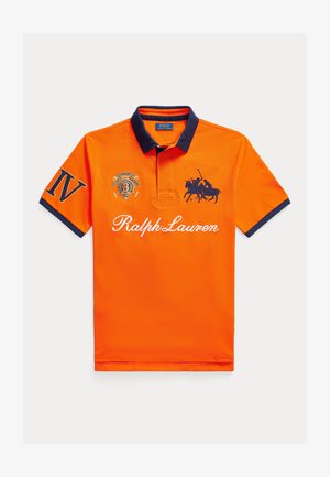 Polo arancione con colletto e polsini blu navy. Presenta un ricamo: un logo sul petto a sinistra e la scritta "Ralph Lauren" sulla parte frontale.