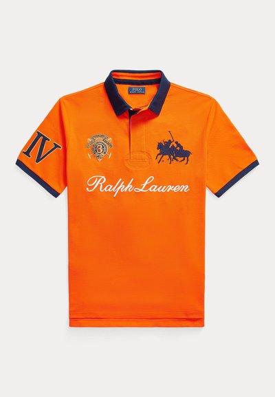 Πορτοκαλί πόλο πουκάμισο με μπλε σκούρο γιακά και μανσέτες. Διαθέτει κέντημα: ένα λογότυπο στο αριστερό στήθος και τη φράση "Ralph Lauren" στο μπροστινό μέρος.