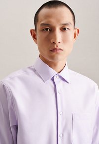 Camicia button-up lilla chiaro con colletto classico, taschino sul petto e texture sottile. Presenta bottoni bianchi e una vestibilità su misura.