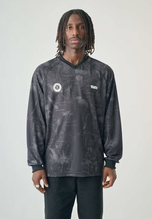 Long-sleeve black shirt with a textured patterned design, featuring a v-neck and logo details on the chest. Soft fabric and relaxed fit.