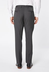 Grau maßgeschneiderte Hose mit glatter Oberfläche, zwei Gesäßtaschen und schmaler Passform, kombiniert mit schwarzen Halbschuhen.