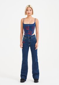 Denim crop top med rød broderi, parret med højtaljede flared jeans. Begge i mørkeblå med en struktureret pasform og minimal hardware.