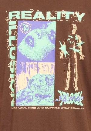 Brun t-shirt med grafiska tryck i blått och persika, inklusive ett ansikte, geometriska former och texten "REALITY" och "DIVIDE YOUR MIND."